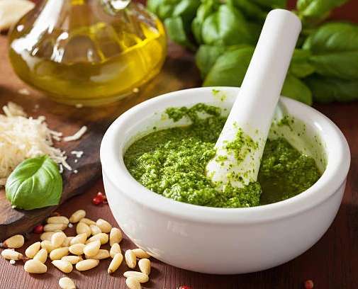 Homemade pesto sauce prepared with a mortar and pestle.