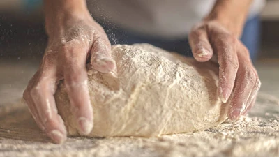 A baker kneading a Sourdough Pizza Dough